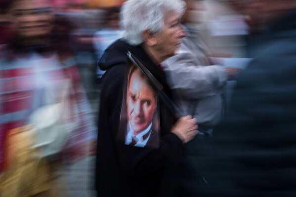 A woman with a image of Turkey's founding father Mustafa Kemal Ataturk marches with others in support of Turkey's main opposition Republican People's Party or (CHP) chairman Ozgur Ozel, in Istanbul, Turkey, Friday, May 22, 2026. (AP Photo/Francisco Seco)
