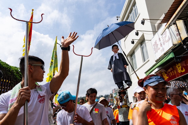 A child is hoisted up during the Piu Sik Parade at the Bun Festival in Cheung Chau Island in Hong Kong, Sunday, May 24, 2026. (AP Photo/Chan Long Hei)
