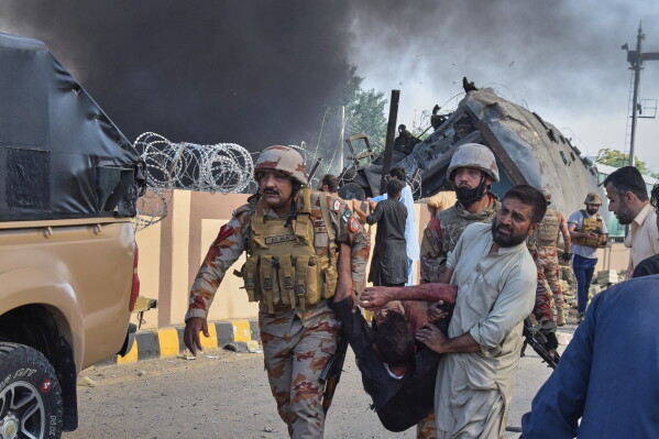 Paramilitary soldiers and a volunteer carry an injured victim after recovering from an overturned train coach on a railway track at the site of a bomb explosion in Quetta, Pakistan, Sunday, May 24, 2026. (AP Photo/Arshad Butt)