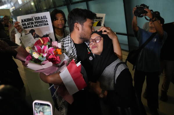 Thoudy Baday, left, Indonesian journalist who was aboard the Global Sumud Flotilla and was detained by Israeli authorities, kisses his mother upon arrival at Soekarno-Hatta International Airport in Tangerang, Indonesia, Sunday, May 24. 2026. (AP Photo/Tatan Syuflana)