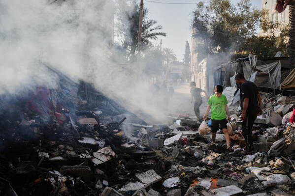 Palestinians walk through the rubble of the Al-Kurd family home, destroyed in an Israeli airstrike in Deir al-Balah, central Gaza Strip, Sunday, May 24, 2026. (AP Photo/Abdel Kareem Hana)