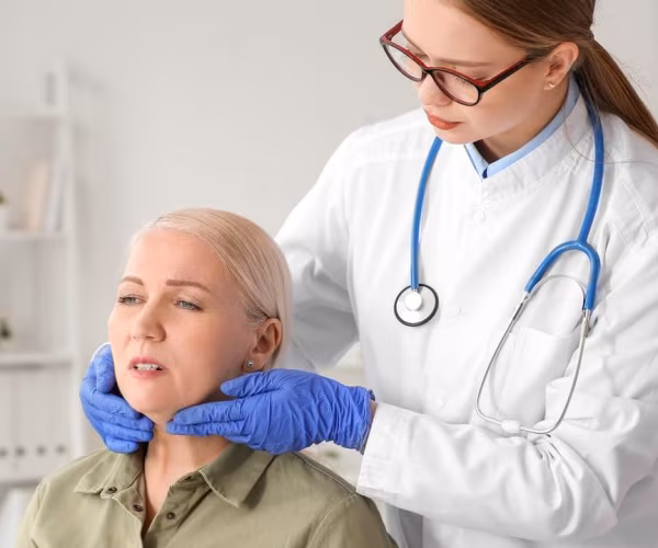 Doctor feeling woman's thyroid