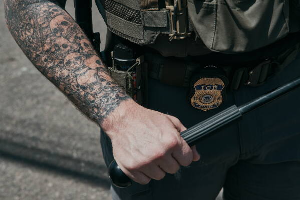 An ICE agent holds his baton, with tattoos of skulls on his arm, outside the Delaney Hall detention during a protest against the transfer of detainees on Tuesday, May 26, 2026, in Newark, N.J. (AP Photo/Andres Kudacki)