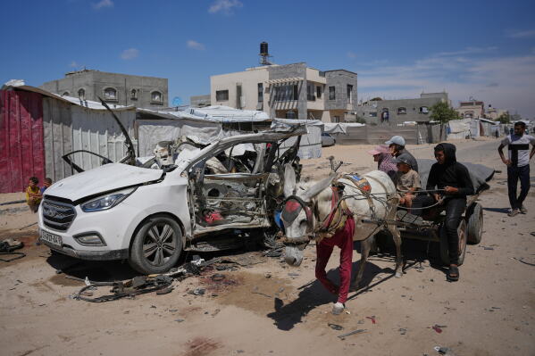 Palestinians inspect a damaged vehicle that was targeted in an Israeli airstrike in Khan Younis, southern Gaza Strip, Tuesday, May 26, 2026. (AP Photo/Abdel Kareem Hana)