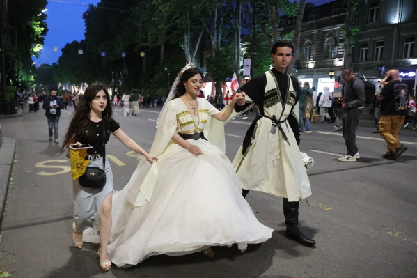 A new married couple in traditional attire attend an opposition rally marking the Independence Day in Tbilisi, Georgia, Tuesday, May 26, 2026. (AP Photo/Zurab Tsertsvadze)