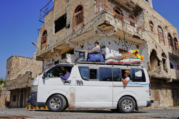 A passenger van drives past a war-damaged building on the eastern frontline after completing security checks to enter the government-controlled city center, ahead of the Islamic Eid al-Adha, in Taiz, Yemen, Tuesday, May 26, 2026. (Photo by Abdulnasser Alseddik)