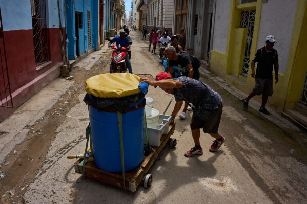 People transport containers of water in Havana, Wednesday, May 27, 2026. (AP Photo/Ramon Espinosa)