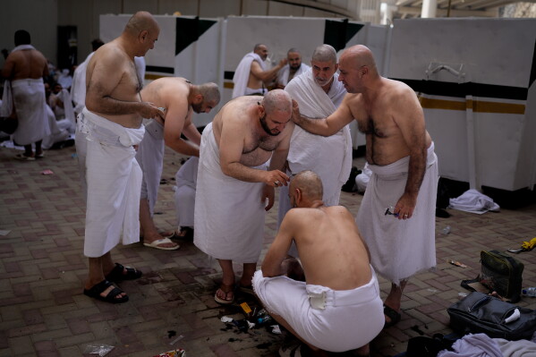 Muslim pilgrims shave each other's heads, during a ritual known as "halq," marking the completion of Hajj after the symbolic stoning of the devil in Mina near the holy city of Mecca, Saudi Arabia, Wednesday, May 27, 2026. (AP Photo/Altaf Qadri)