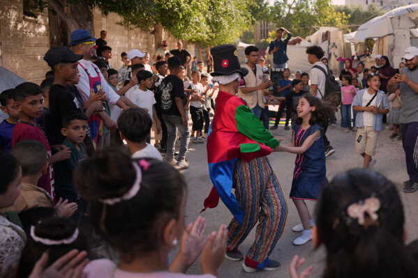 Palestinian clown Mohammed Salem, 18, dances with a girl as he performs on a street during Eid al-Adha celebrations in Gaza City, Thursday, May 28, 2026. (AP Photo/Abdel Kareem Hana)