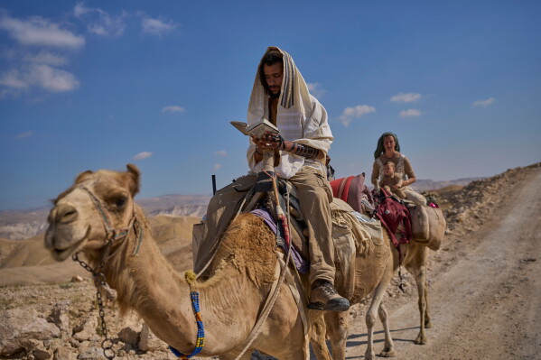 Israeli settler parents travel with their baby on camels in the northern Judean Desert near the settlement of Maale Adumim, in the West Bank, Thursday, May 28, 2026. (AP Photo/Ohad Zwigenberg)