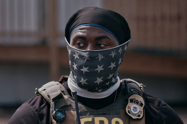 A masked ICE agent stands guard outside the Delaney Hall detention during a protest against the transfer of detainees on Tuesday, May 26, 2026, in Newark, N.J. (AP Photo/Andres Kudacki)