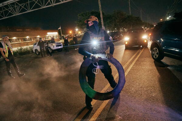 An ICE agent removes a tire from the road as agents clash with protesters outside the Delaney Hall detention center, Wednesday, May 27, 2026, in Newark, N.J. (AP Photo/Andres Kudacki)