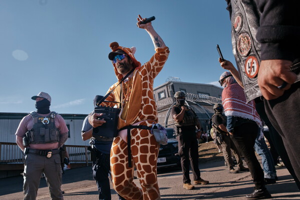 A protester performs in front of ICE agents outside the Delaney Hall detention center while demonstrating near the entrance gates, Wednesday, May 27, 2026, in Newark, N.J. (AP Photo/Andres Kudacki)