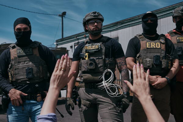A protester holds her hands up as ICE agents guard the Delaney Hall detention center during a protest against the transfer of detainees on Tuesday, May 26, 2026, in Newark, N.J. (AP Photo/Andres Kudacki)