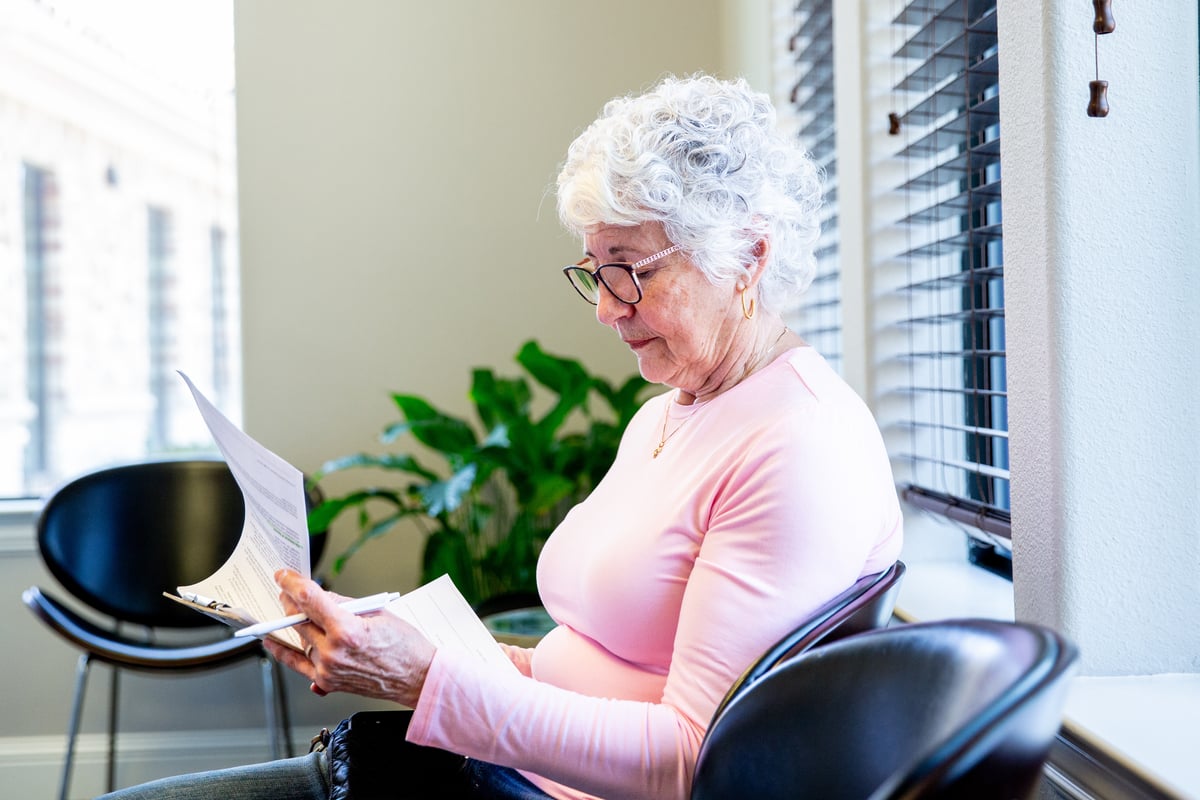 A person filling out a form in a waiting room.
