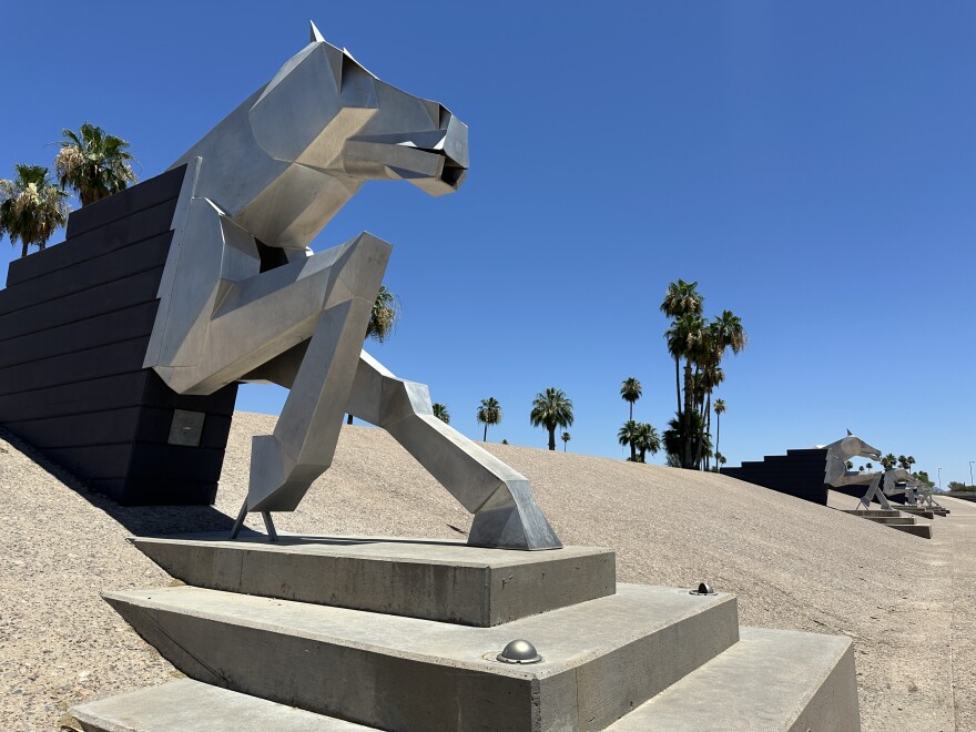 A 14-foot tall metal horse sculpture juts out from a concrete wall
