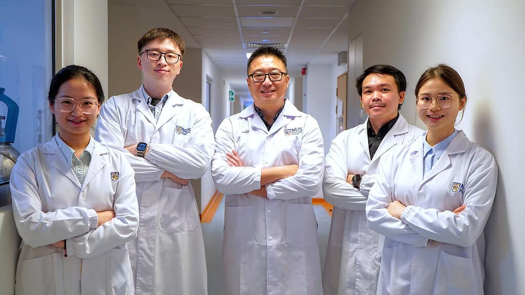 Research team posing arms crossed in lab coats for a photo