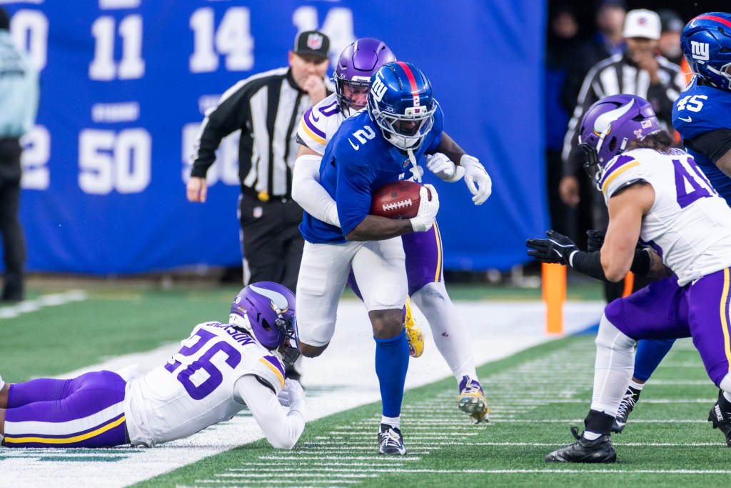 New York Giants player Deonte Banks runs the ball as Minnesota Vikings player Ivan Pace Jr. tackles him.