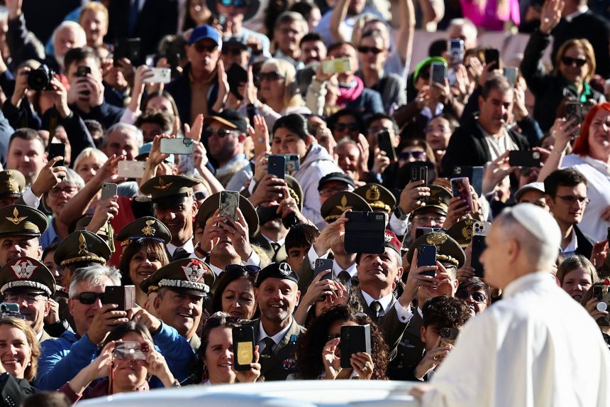 Faithful use their mobile phones as Pope Leo XIV arrives for a general audience in St. Peter's Square at the Vatican, on October 8.