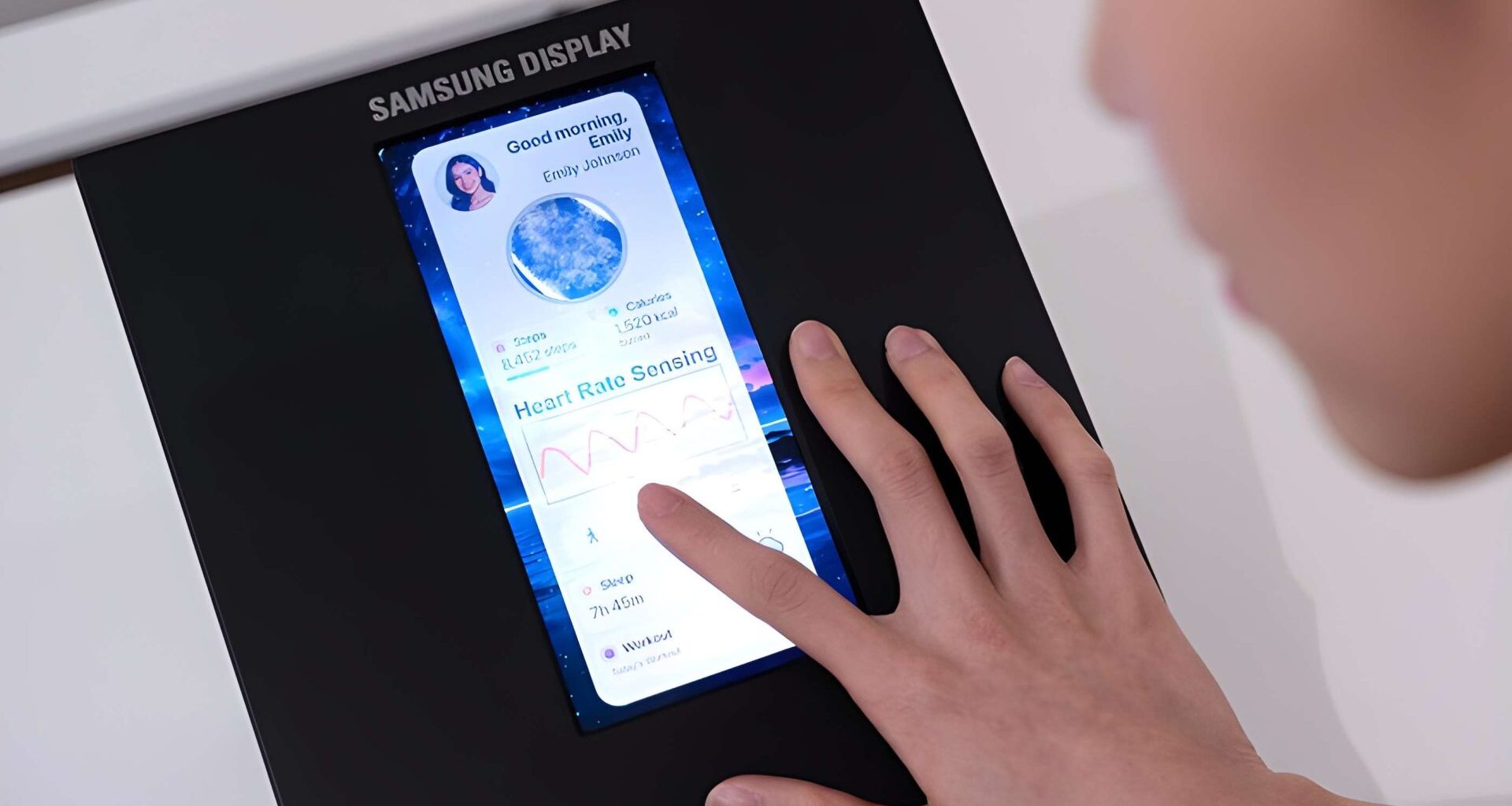 A person interacts with a Samsung Display screen showing health metrics and 'Heart Rate Sensing.'