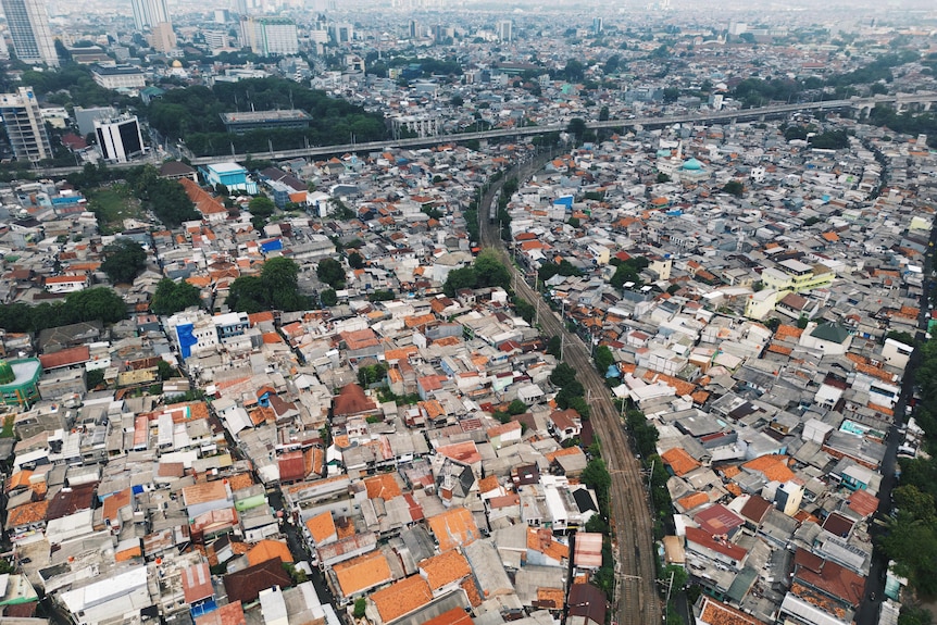 An aerial view of the city of Jakarta, with buildings and houses bisected by roads.