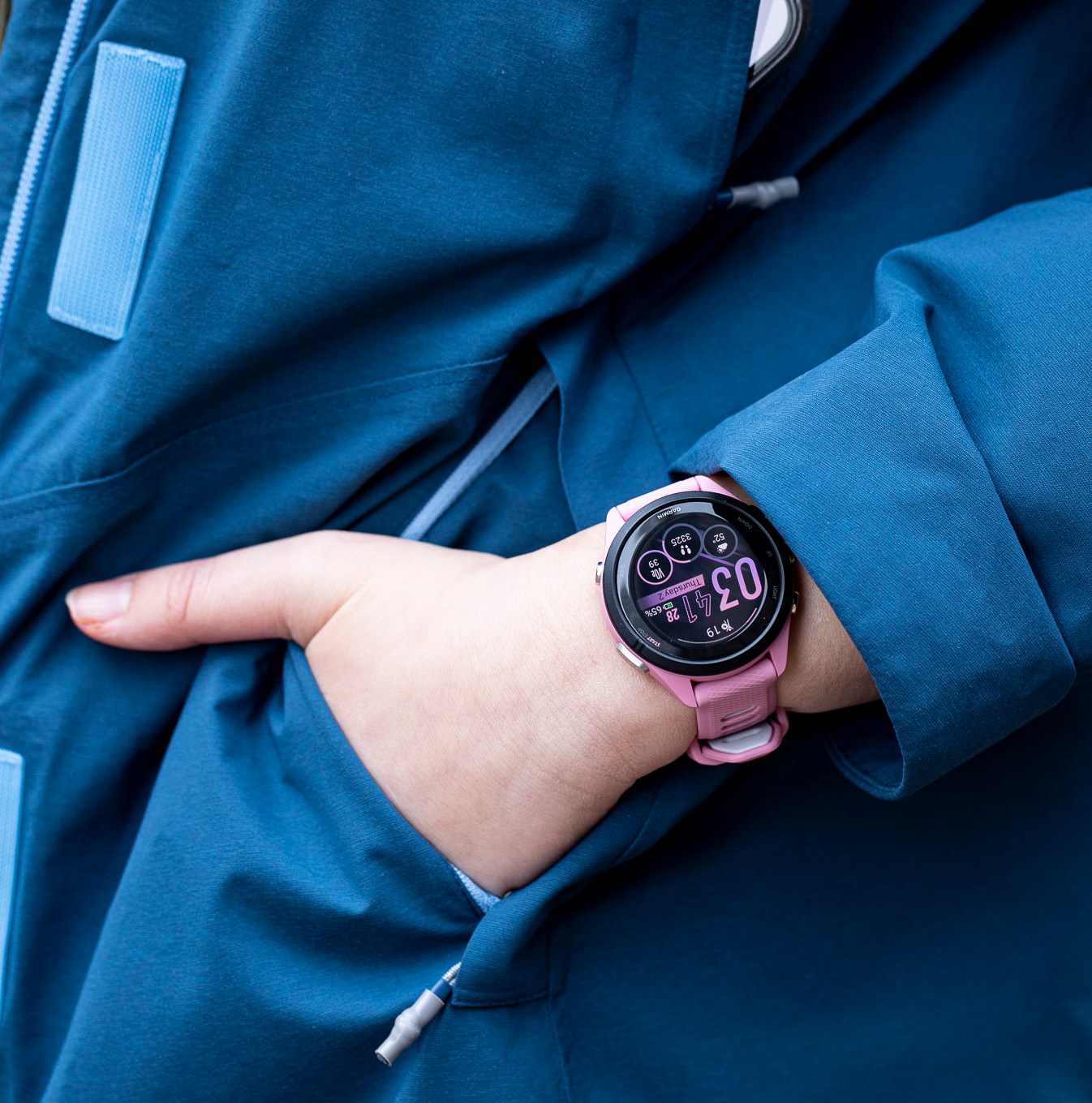 Close-up of the Garmin Forerunner 265S on the wrist of a person putting their hand into a jacket pocket.
