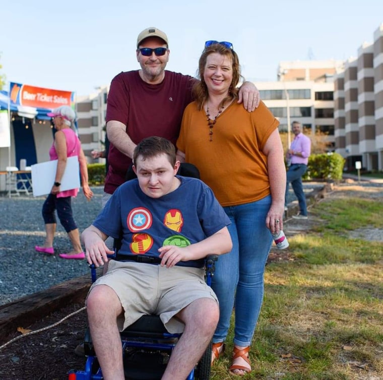 Michele Gregory and her partner and son (in a wheelchair) pose for a family portrait outside