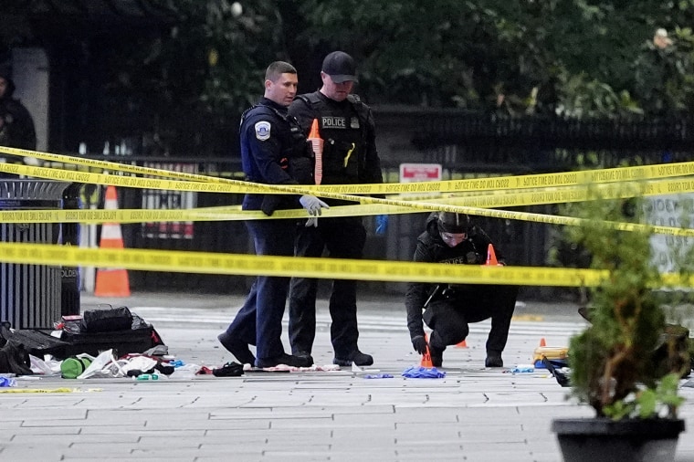 Yellow Crime scene tape stretches across the frame in front of police officers.