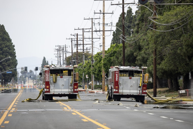 Two red fire trucks parked in the middle of a street.