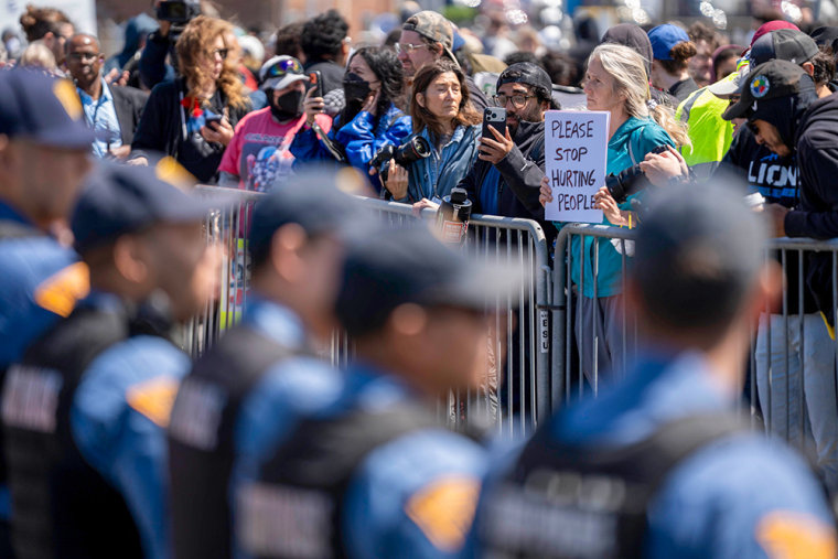 An anti-ICE protesters holds a sign opposing a line of New Jersey State Police.
