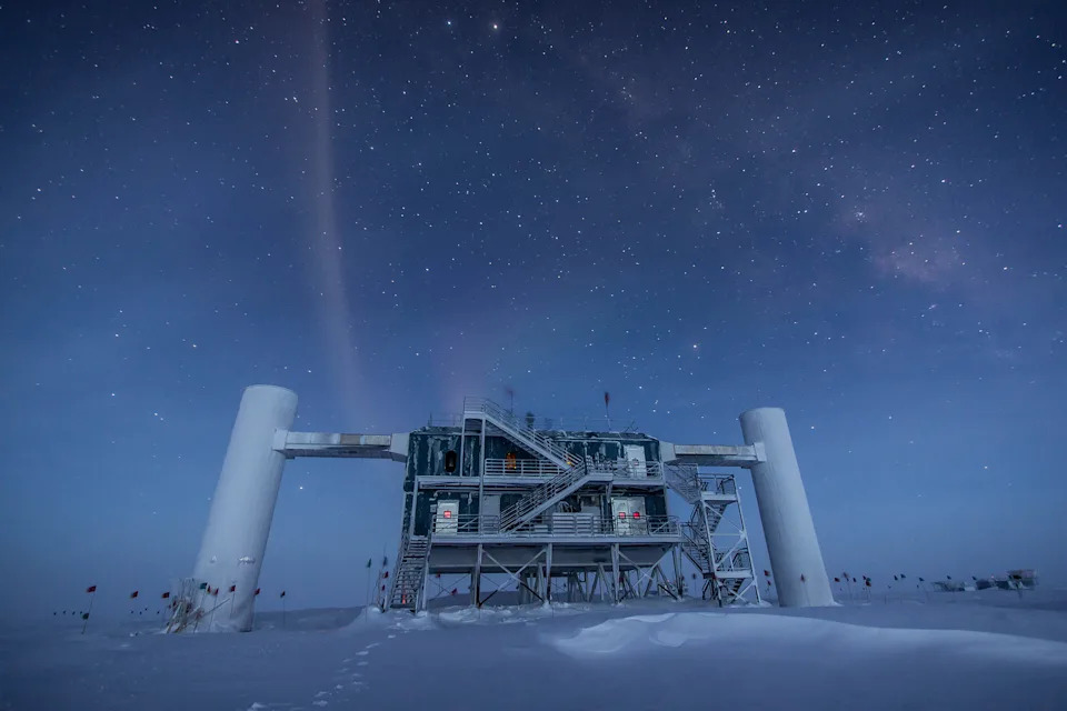 an industrial-looking building covered in catwalks and stairwells sits on a snow-covered tundra