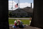 The Washington state, American and Nippon Dynawave flags fly at half-staff while flowers mark a makeshift memorial on old mill equipment in front of Nippon Dynawave Packaging Co. for the at least nine victims of the May 26 chemical disaster, in Longview, Wash., on May 29, 2026.