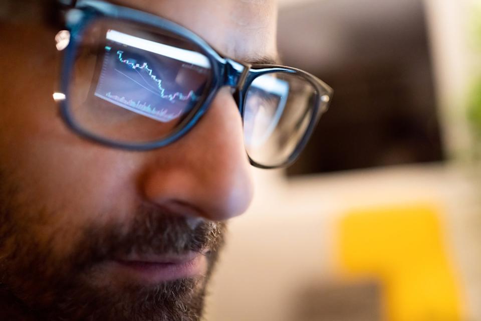 Close-up of a person's face, as they look at a stock chart.