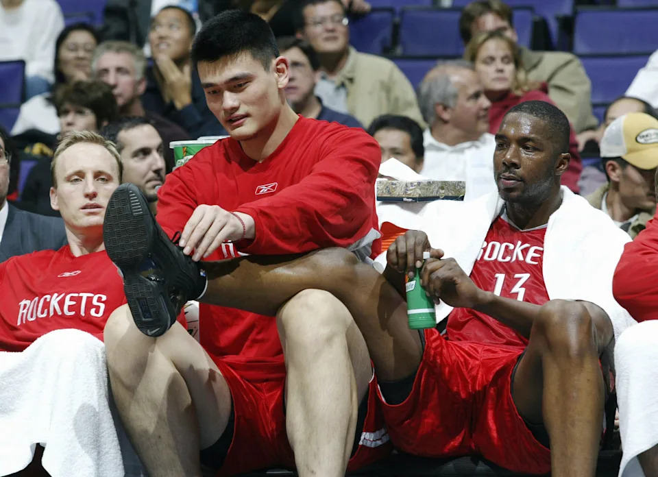 LOS ANGELES - NOVEMBER 24: Yao Ming #11 of the Houston Rockets plays with his teammate Kelvin Cato's shoe laces in the second half of the game against the Los Angeles Clippers on November 24, 2003 at the Staples CenterLos Angeles, California. NOTE TO USER: User expressly acknowledges and agrees that, by downloading and/or using this Photograph, User is consenting to the terms and conditions of the Getty Images License Agreement.(Photo by Robert Laberge/Getty Images)