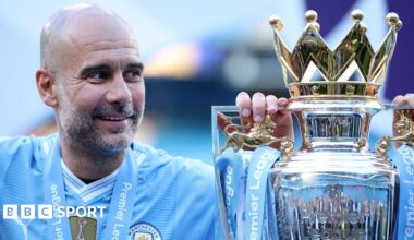 A smiling Pep Guardiola alongside the Premier League trophy in a previous season