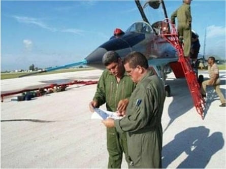 tow men in uniform study papers in front of a military jet