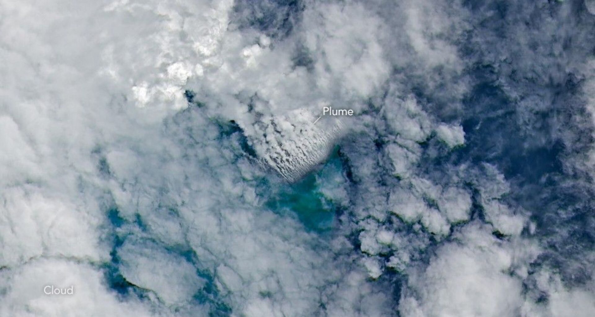 A bunch of clouds over very blue water. In the center, an arrow points to where the volcanic plume is seen.