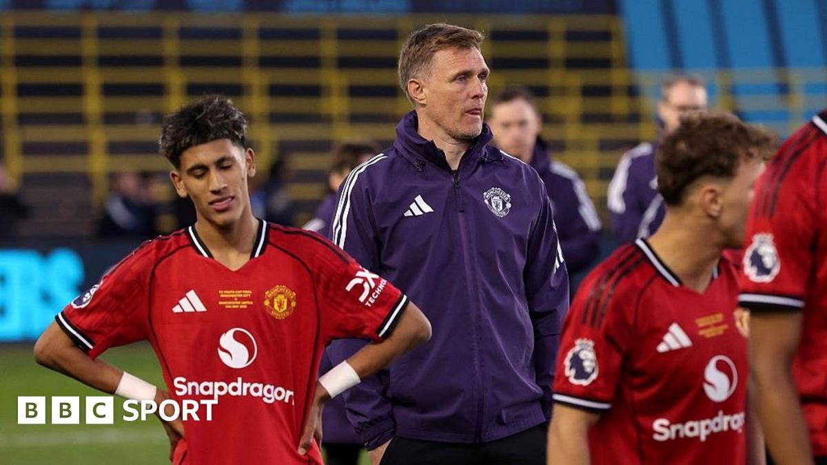 Manchester United Under-18 coach Darren Fletcher, in purple tracksuit top, stands between two of his players, who both wear red match kit