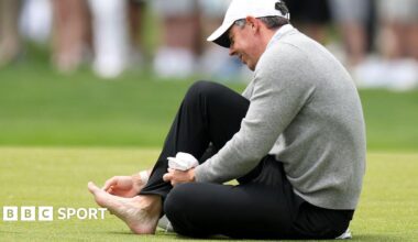 Rory McIlroy attending to his sore toe while on the third fairway at Aronimink Golf Club