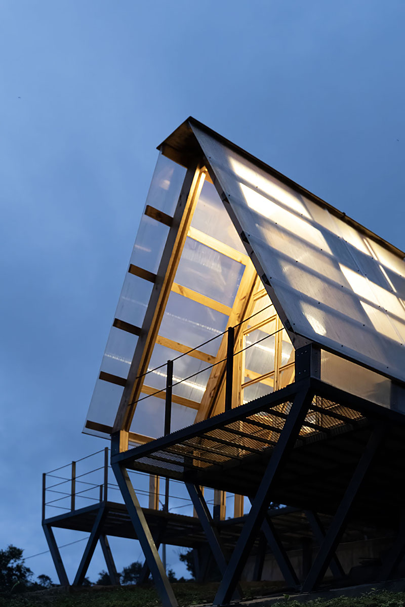 translucent polycarbonate skin envelopes triangular shelter elevated on stilts in ecuador - 11