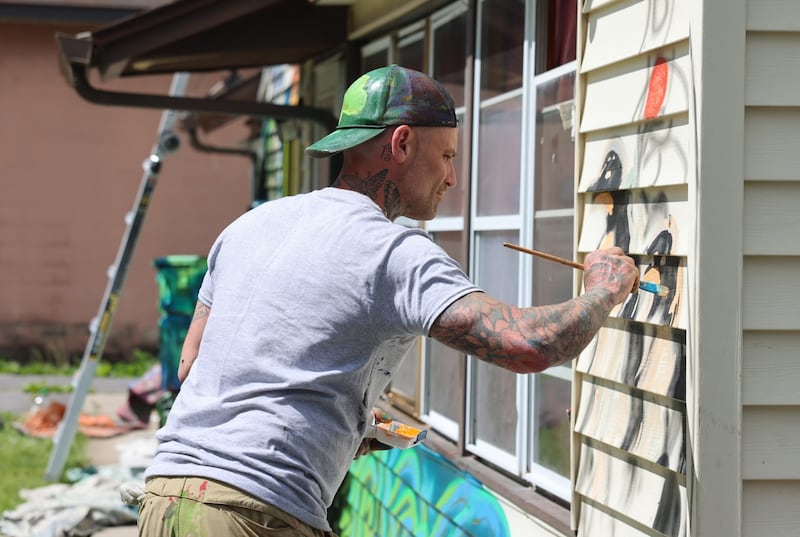 Artist David Smart paints penguins as part of his zoo-inspired mural on the rental property at 521 S. Wilbur Ave.