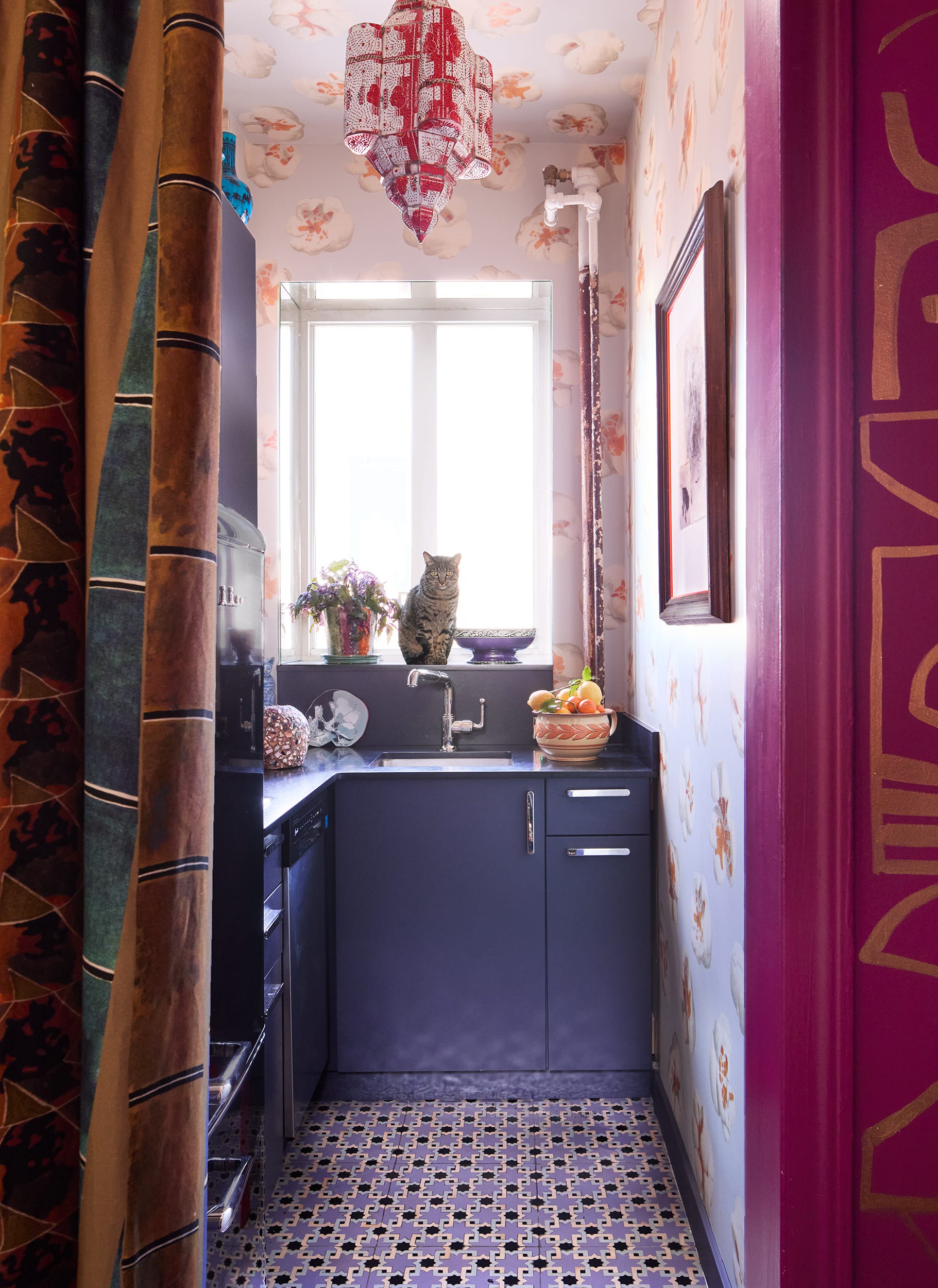 Colorful kitchen with a cat sitting on the counter.