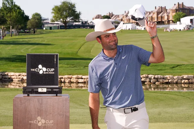 Scottie Scheffler celebrates with the winner's trophy during the final round of the THE CJ CUP Byron Nelson golf tournament. Scheffler won with a score of 31-under par for the tournament.