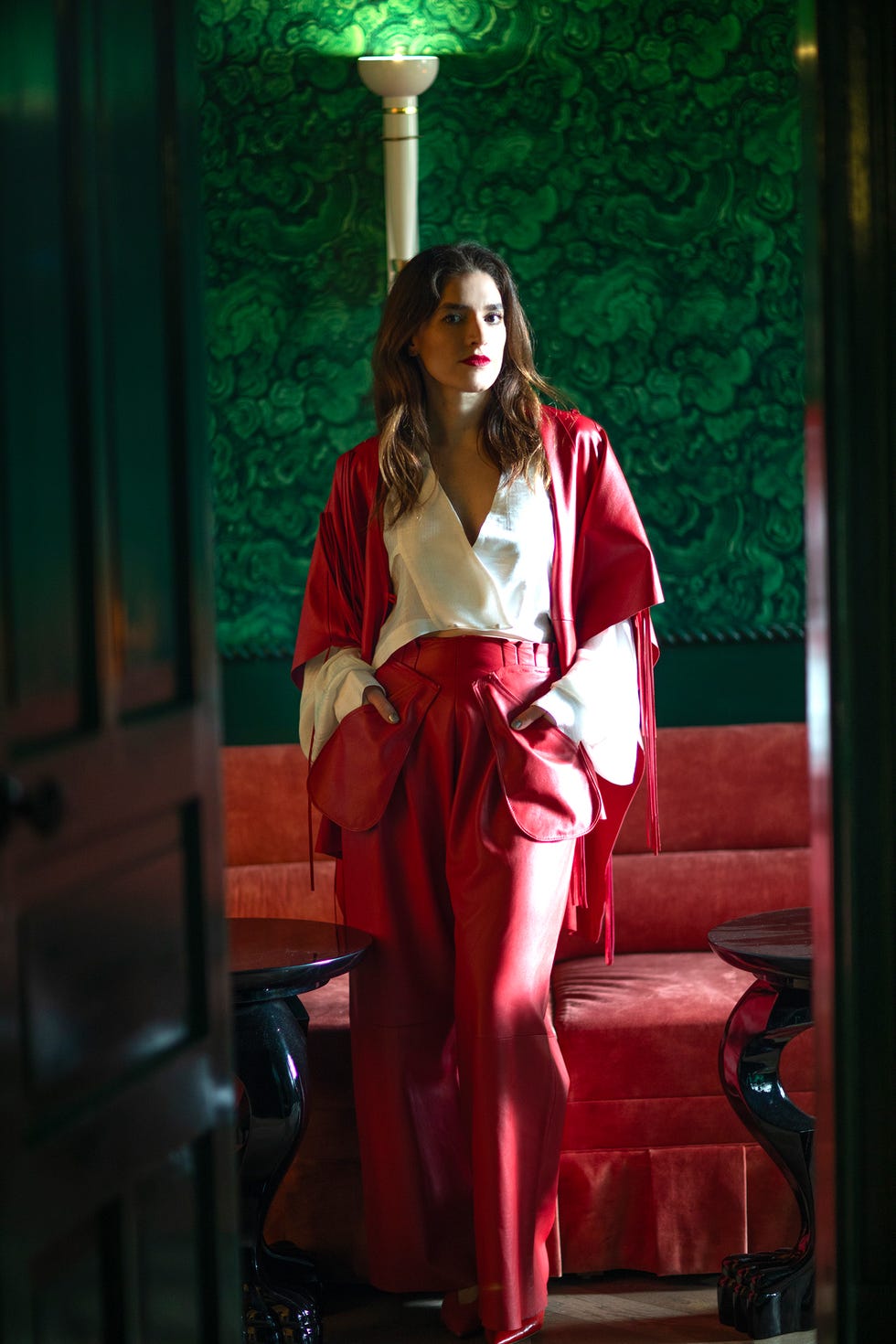 Fashion model in red attire posed in an elegant setting.