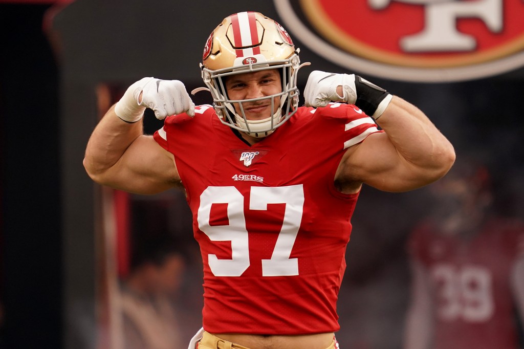 Nick Bosa, wearing a red #97 49ers jersey and helmet, flexes his biceps.