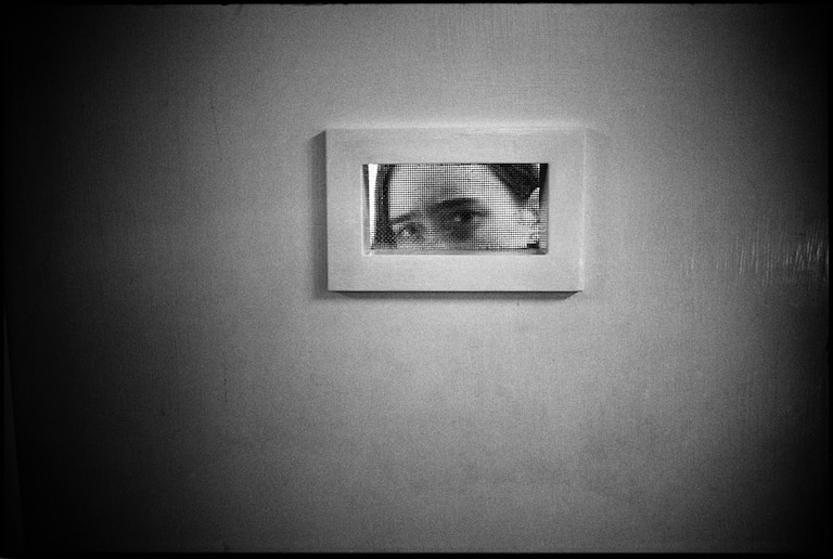 Mary Ellen Mark, [Tommie peeking out of room window, Ward 81, Oregon State Hospital, Salem, Oregon, USA], 1976.