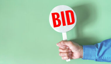 Businessman hold a bid sign Buying, Bidding Concepts, Wooden sign with the word Bid