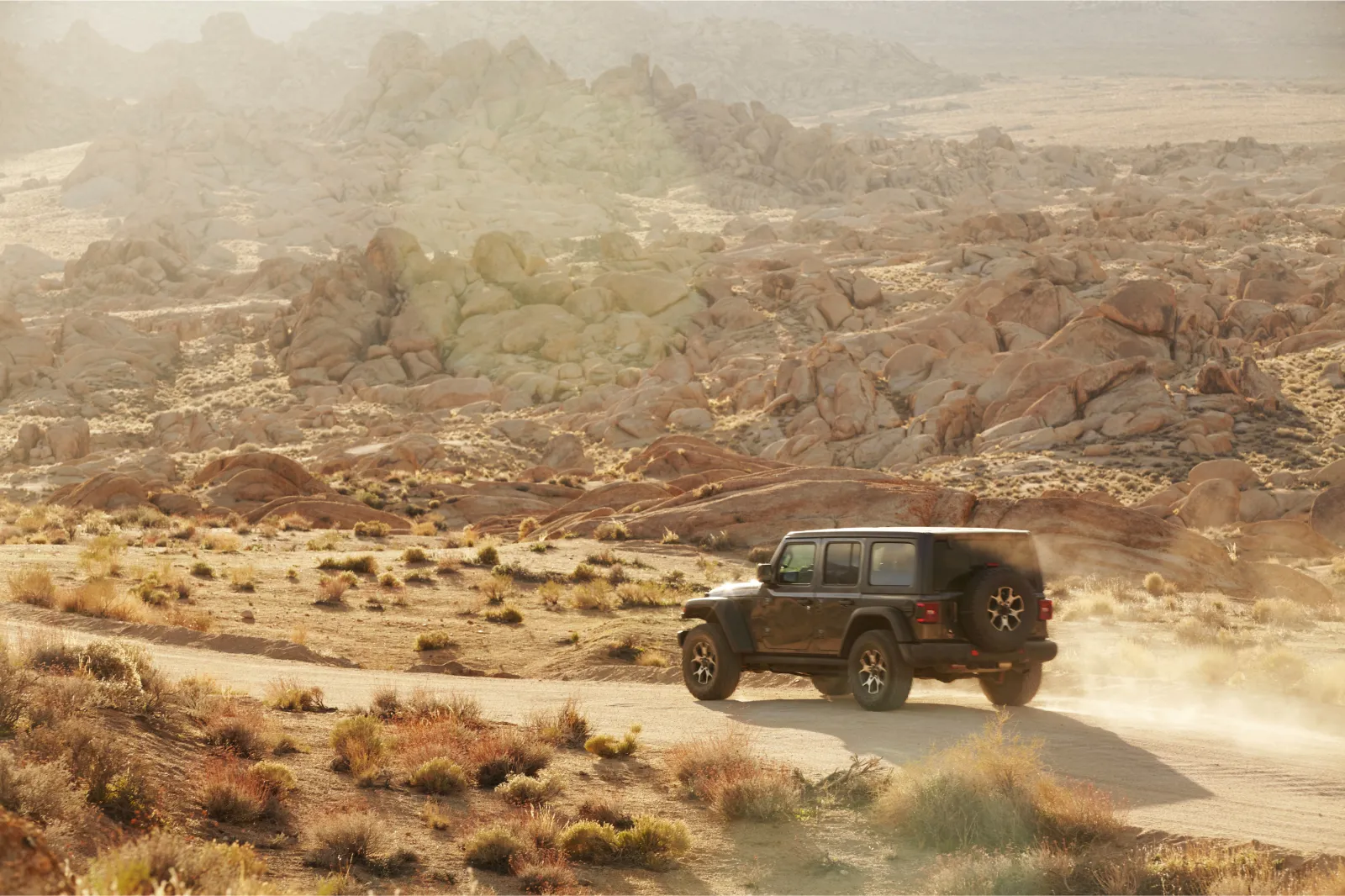 Off road car driving on a dirt road in desert landscape, Alabama hills, California.