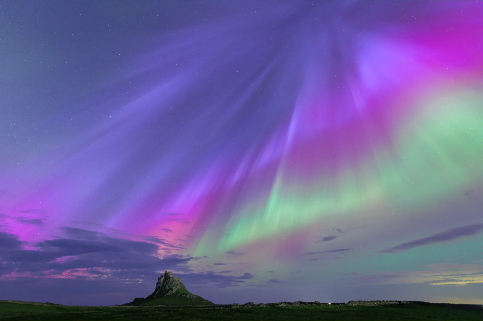 The northern lights, also known as the aurora borealis, with the Lindisfarne Fort on Holy Island, Northumberland, England, in the background.
