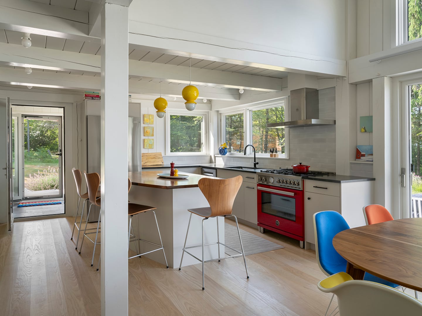 Larger windows pulled to the corner in the kitchen provide better light and a solid wall for the range. The perimeter countertops are a durable black stone while the island, curved to ease circulation, is walnut.